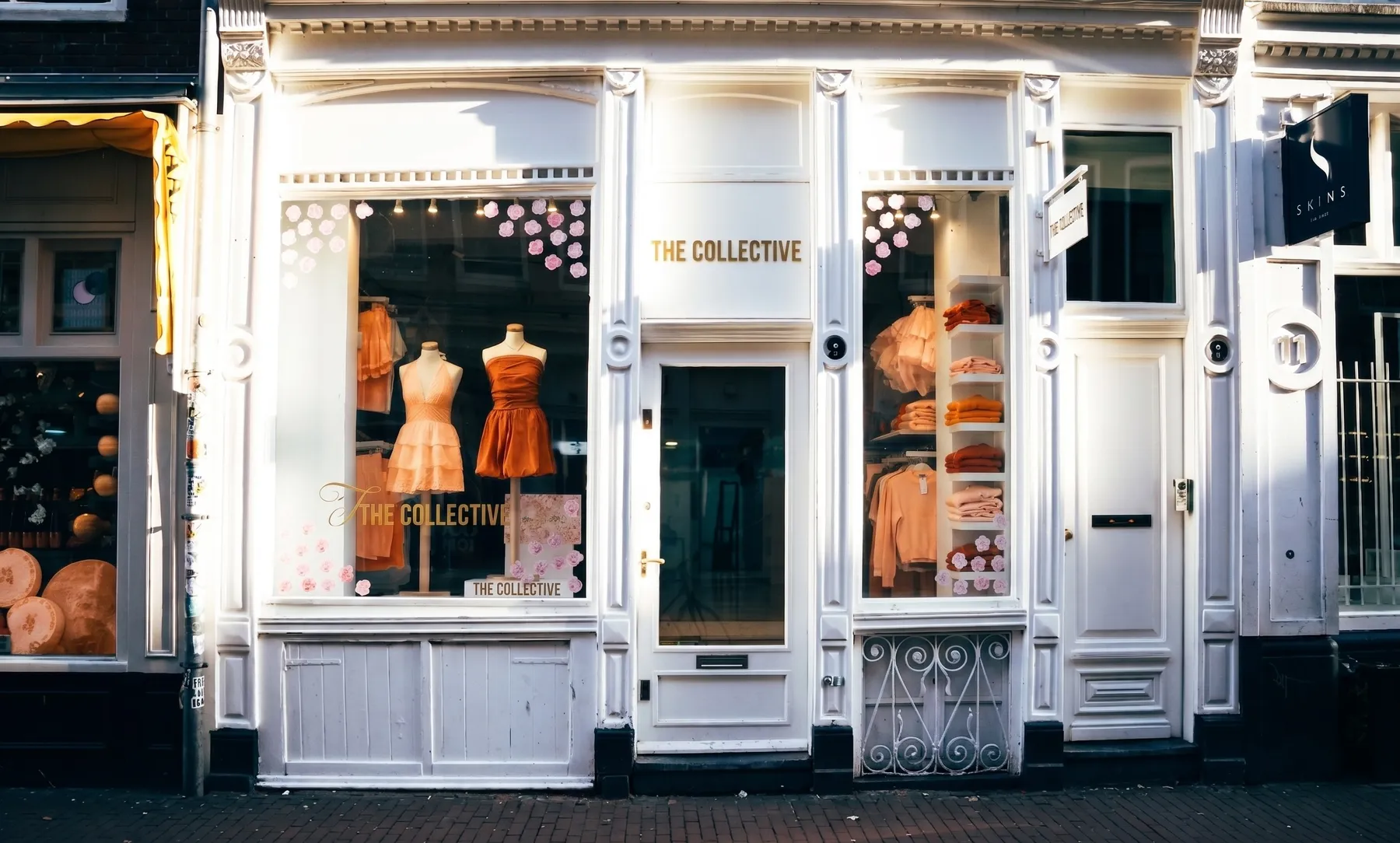 A boutique clothing storefront with coral dresses in the window
